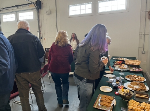Leslie Cameron waits to pour wine as others enjoy the snacks and music.